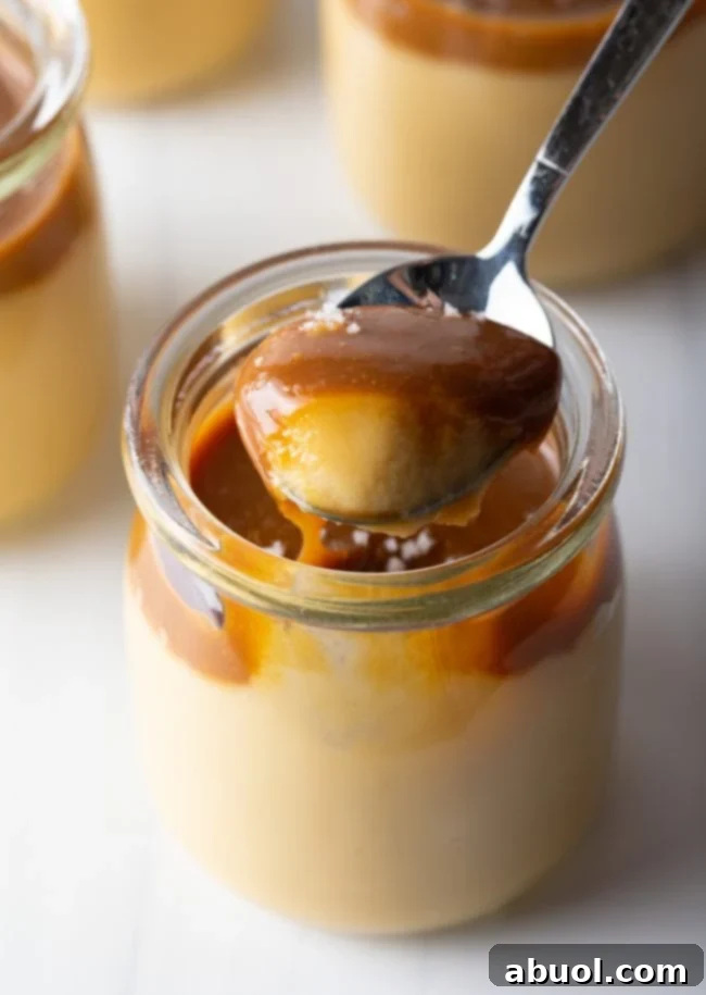 A spoon scooping creamy budino with a perfect blend of butterscotch pudding and salted caramel topping
