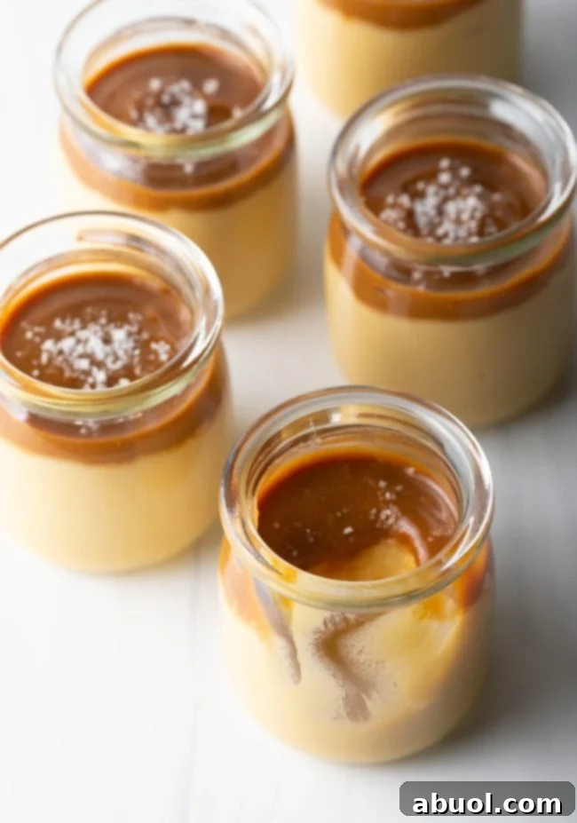 An empty glass jar, with a spoon beside it, showing where a scoop of delicious budino has been removed