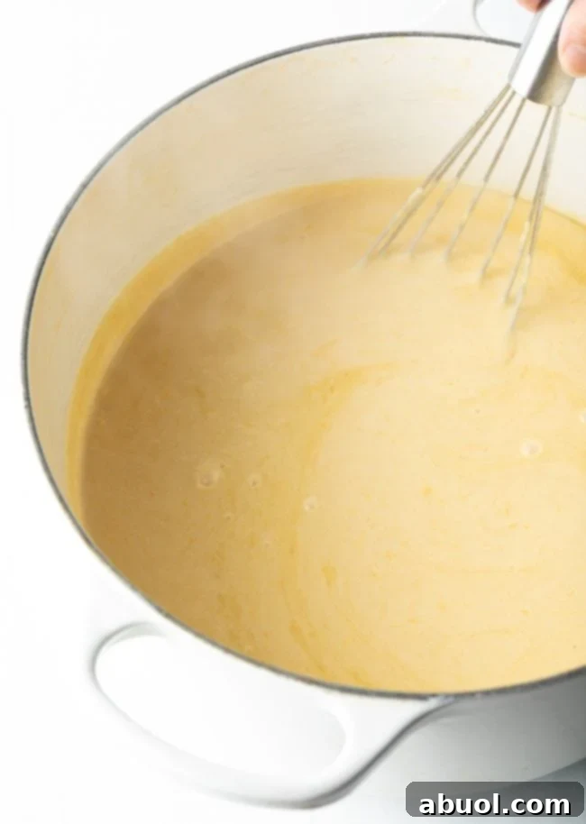 Hands whisking egg yolks, half and half, and cornstarch together in a mixing bowl until smooth