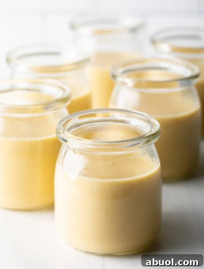 Assortment of glass jars filled with butterscotch budino, some topped with caramel and sea salt, ready for chilling