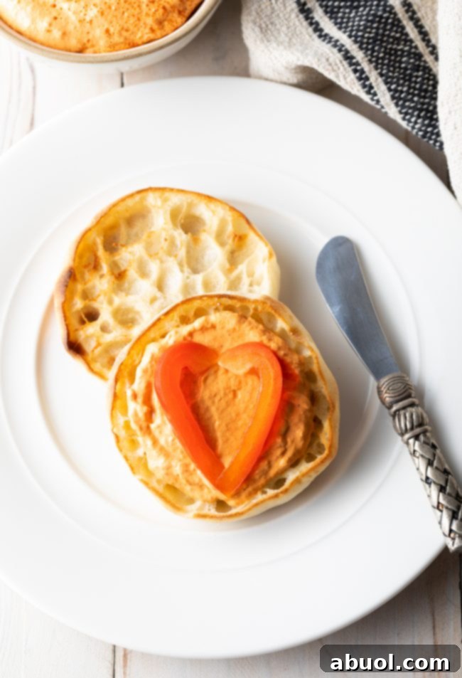 Roasted Red Pepper dip on an English muffin with a butter knife next to it. 