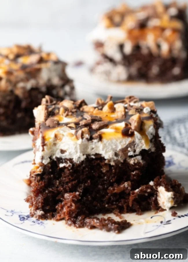 Close-up view of a slice of Better Than Sex Cake, showcasing moist chocolate cake, rich caramel sauce, fluffy whipped topping, and chopped Heath bars