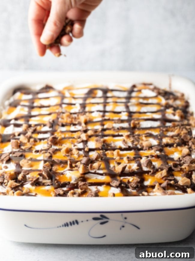 Finished Better Than Sex Cake, garnished with chocolate and caramel sauce drizzles and extra chopped Heath bars on a bed of whipped cream