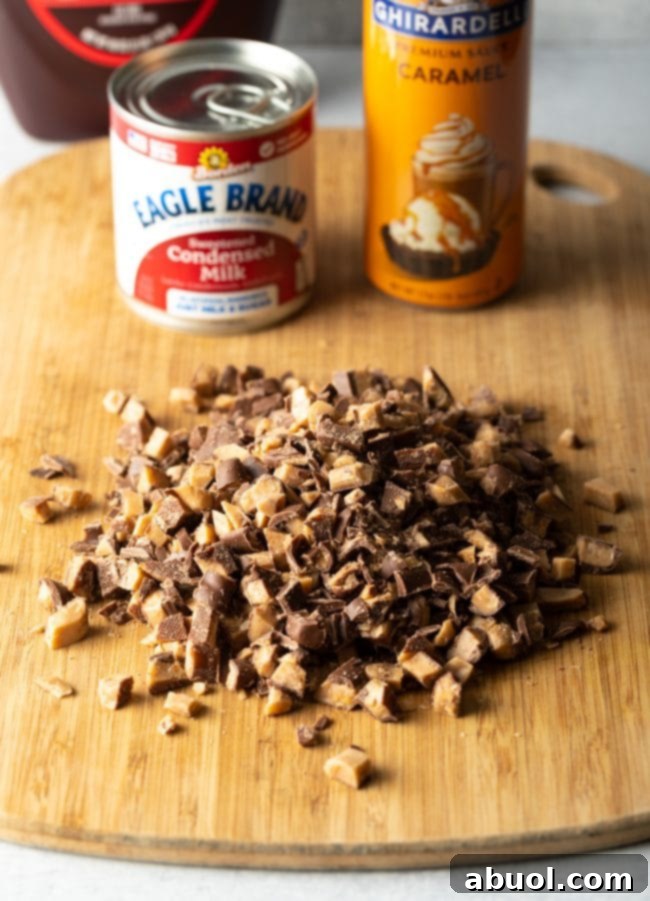 Wooden cutting board displaying chopped toffee bars, with a can of condensed milk and a bottle of caramel sauce in the background