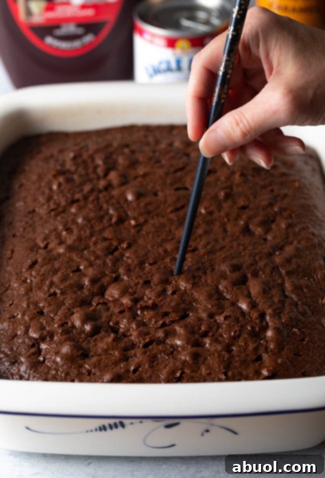 Using a chopstick to poke holes into a freshly baked Devil's food cake