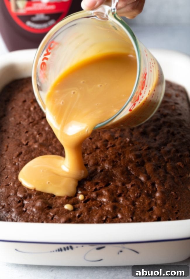 Close-up of caramel sauce being poured into poked holes of a chocolate cake