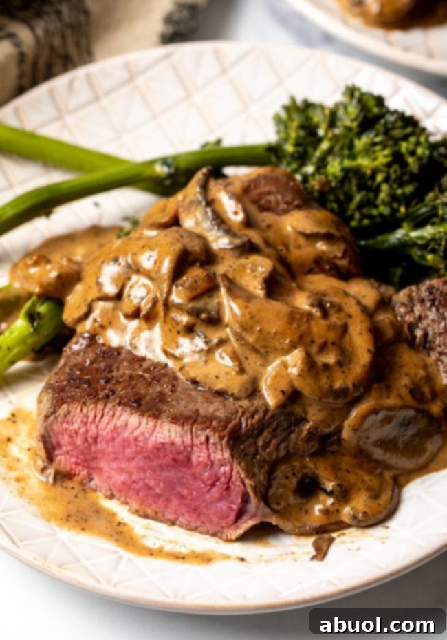 Cheesecake Factory's Iconic Steak Diane 11 View of sliced steak on a white plate, topped with mushroom cream sauce. A close-up of tender, sliced Steak Diane.
