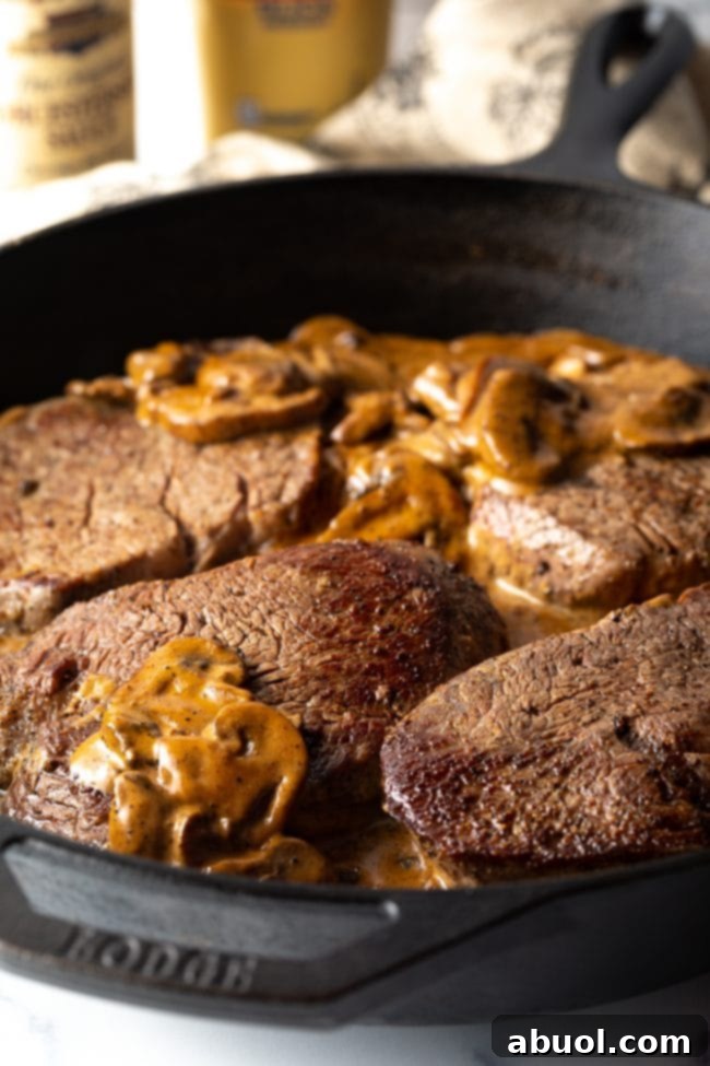 Cheesecake Factory's Iconic Steak Diane 8 4 steaks sitting in a mushroom cream gravy in a cast iron skillet. Steak Diane finishing in the sauce.