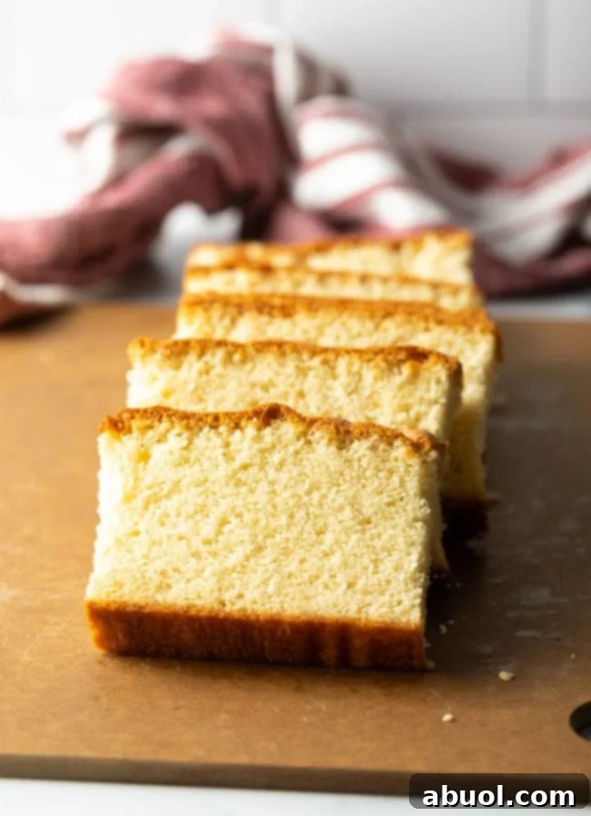 Slices of golden Japanese Castella sponge cake arranged on a rustic brown cutting board, showcasing its light and airy texture.