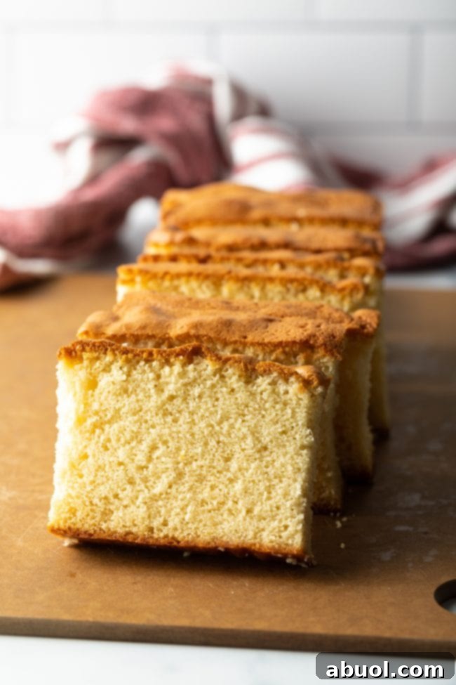 A beautiful stack of sliced Castella Japanese sponge cake resting elegantly against each other on a brown cutting board, inviting a taste.