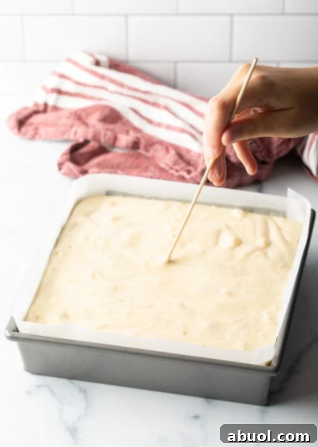 Delicate Castella cake batter poured smoothly into the meticulously prepared parchment-lined baking pan, ready for the oven.