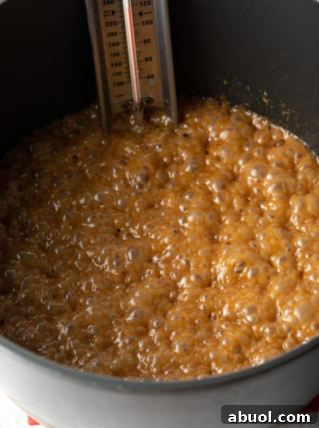 Large pot on a stove with caramel mixture bubbling vigorously, showing the transformation of sugar into a molten, amber liquid.