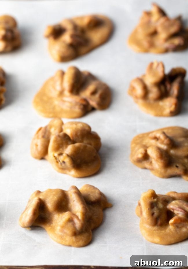 Top-down view of numerous homemade candies meticulously arranged on parchment paper, undergoing the cooling process and solidifying.