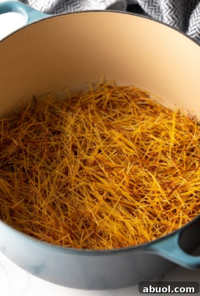Broken pasta browning in a large pot with olive oil.