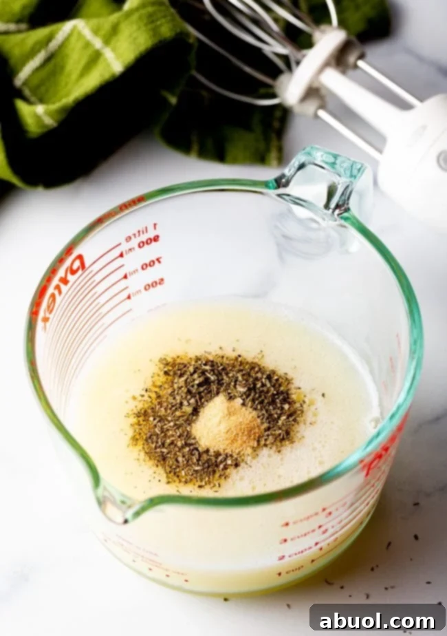 frothy egg whites in a measuring glass with seasonings, showing the key to a light and airy frittata.