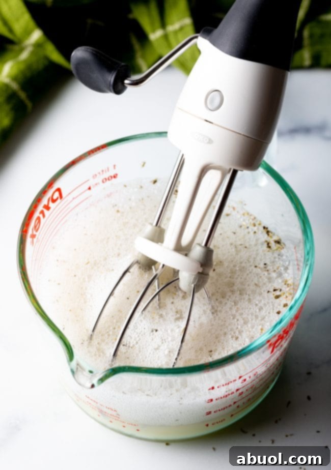 using a hand mixer to beat ingredients in the measuring glass until frothy, an essential step for a perfect egg white frittata.