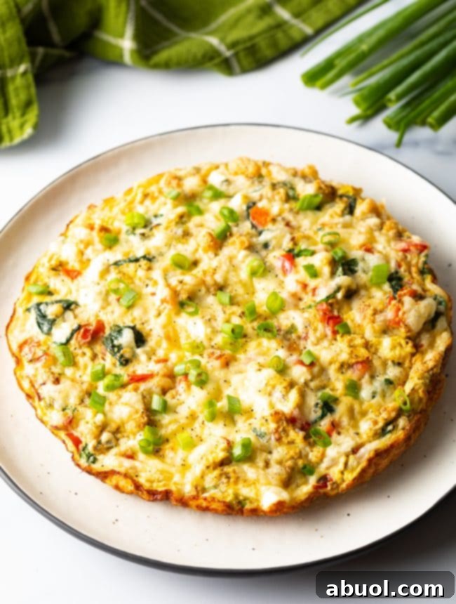 egg white frittata on serving platter with scallions on top, ready to be enjoyed as a healthy meal.