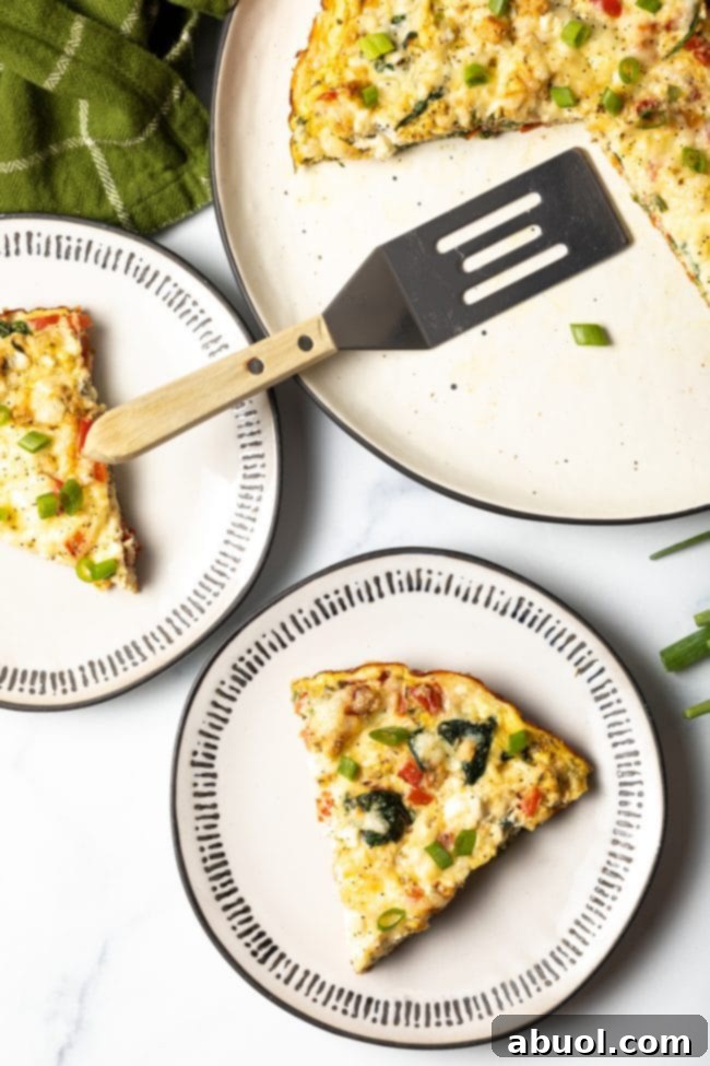top down view baked egg white spinach and veggie frittata slices on two plates with full baked dish and spatula off to the side, emphasizing easy meal prep.