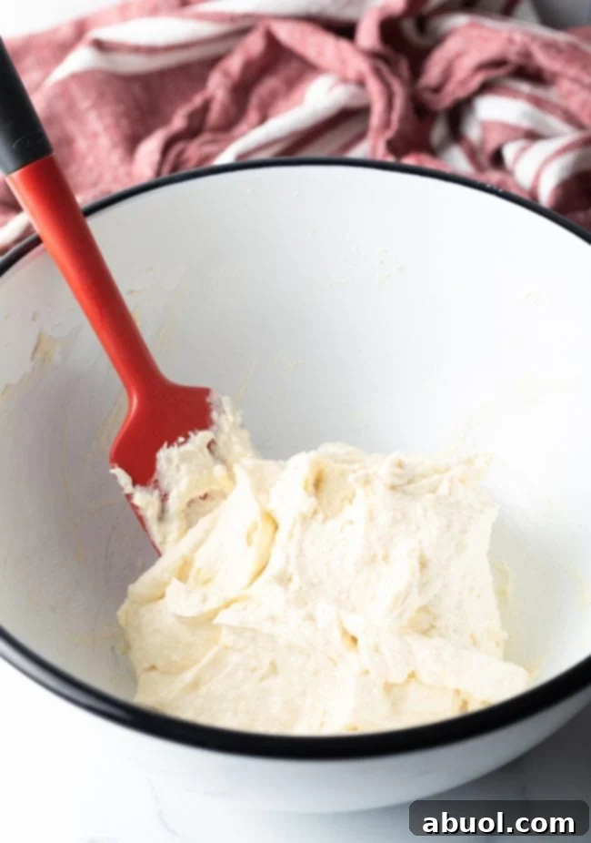 Large mixing bowl with red spatula combining cream cheese mixture.