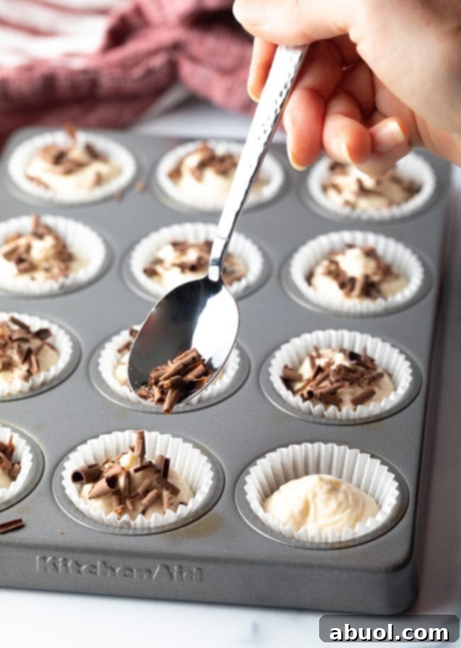 Hand with spoon adding shaved chocolate to the no-bake cream cheese cheesecake bites.