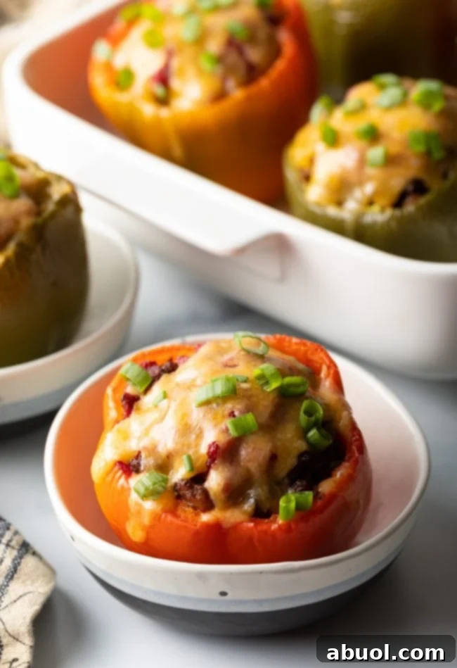 Red bell pepper stuffed with ground beef, topped with melted cheese and chopped scallions, set in a white bowl.