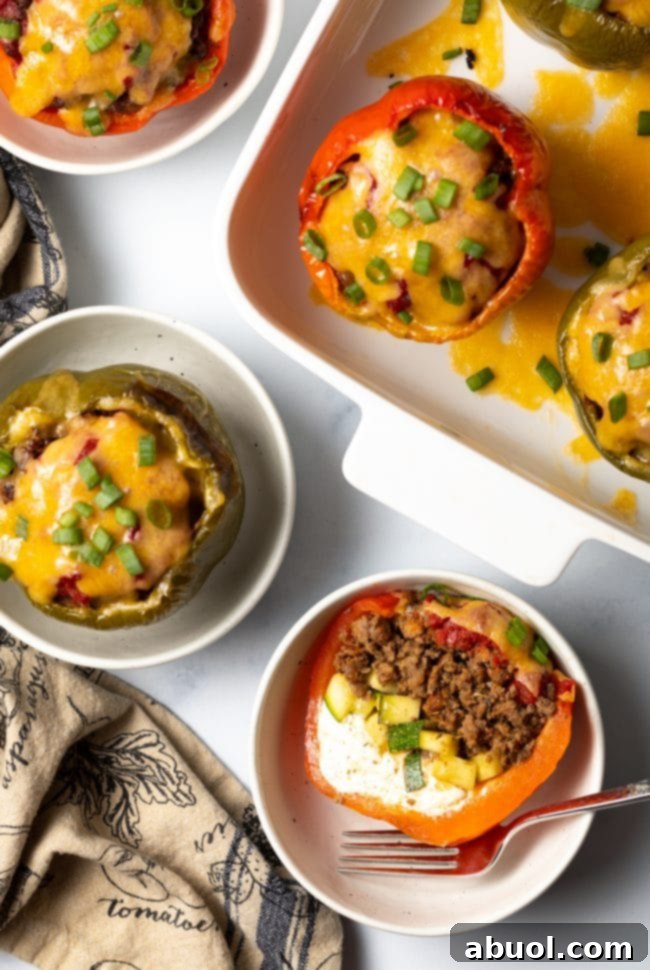 Top view keto stuffed peppers, one cut in half to show ground beef, zucchini, and cream cheese, set in a white bowl.