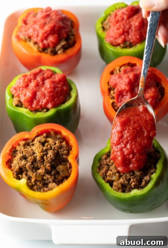 Adding crushed tomato sauce to the ground beef stuffed in raw bell peppers.