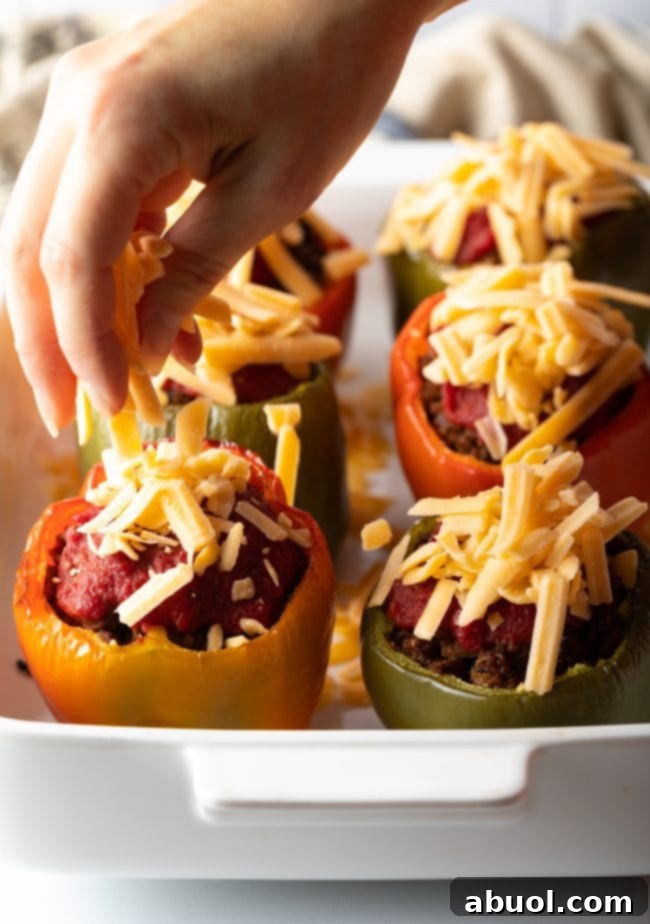 Sprinkling shredded cheese onto to the keto stuffed peppers.