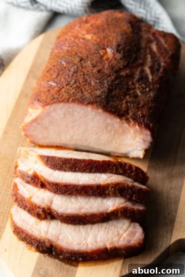Ultimate Smoked Pork Loin Rub 2 Smoked Pork Loin Rub - carved smoked pork loin on a wood board, showcasing its juicy interior and crispy crust