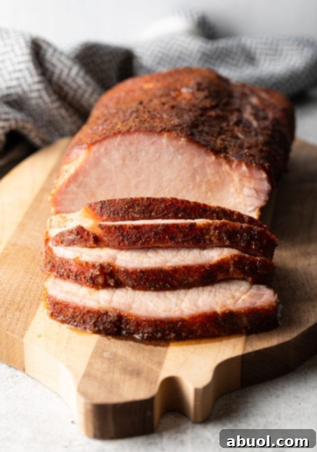 Ultimate Smoked Pork Loin Rub 11 close view of sliced smoked pork loin on a cutting board, emphasizing the moistness