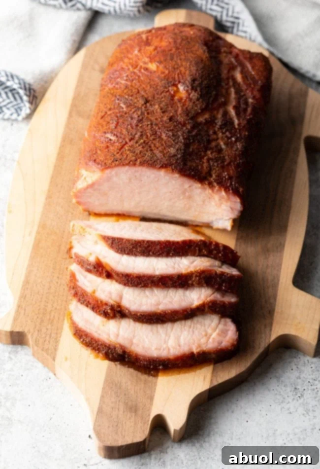 Ultimate Smoked Pork Loin Rub 3 Smoked Pork Loin Rub - top view of a beautifully sliced smoked pork loin on a cutting board