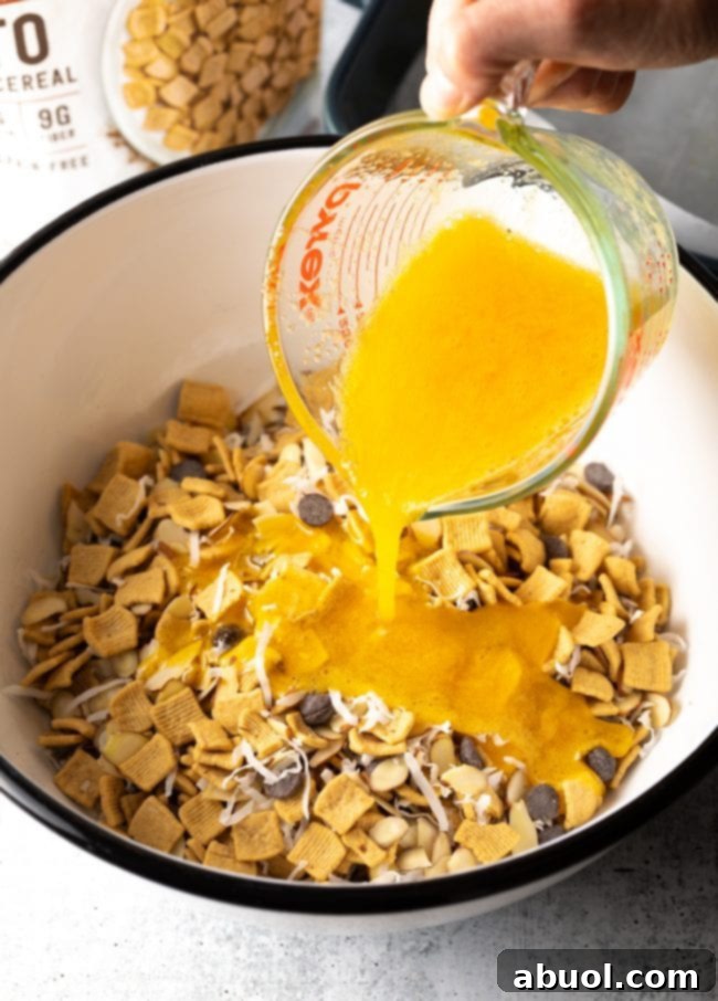 Low Carb Keto Cereal Snack Bars 5 Adding whisked egg to the cereal, chocolate chips, shredded coconut, and nuts in the mixing bowl.