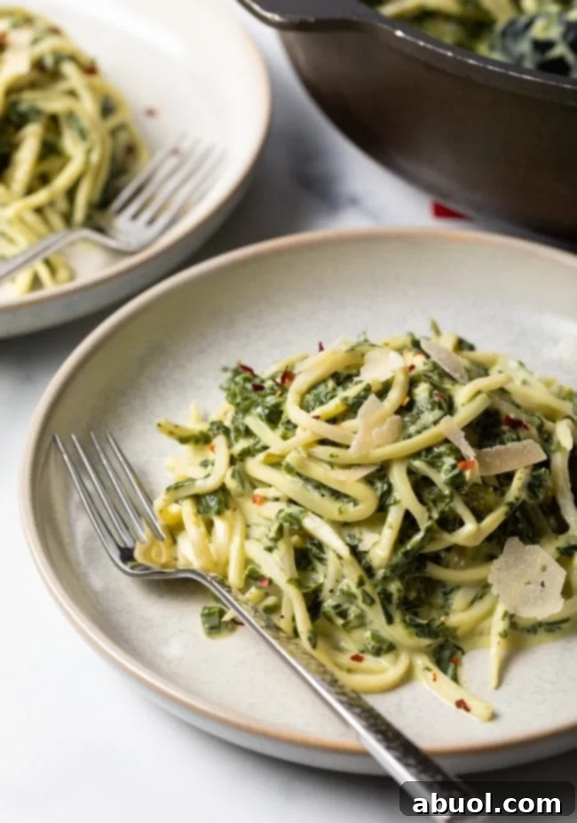 Close-up view of a plate of hearts of palm pasta twirled on a fork, showcasing the creamy spinach sauce.