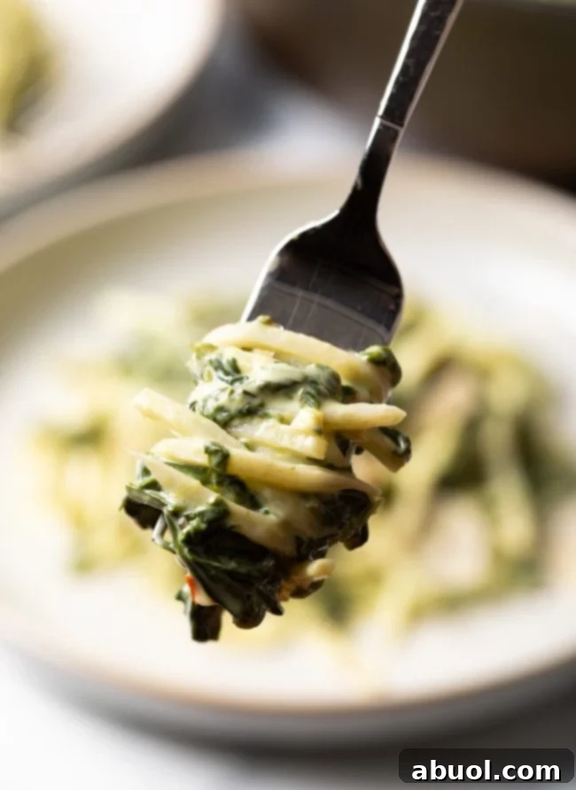 A fork twirling hearts of palm linguine, showing its pasta-like texture and creamy coating.