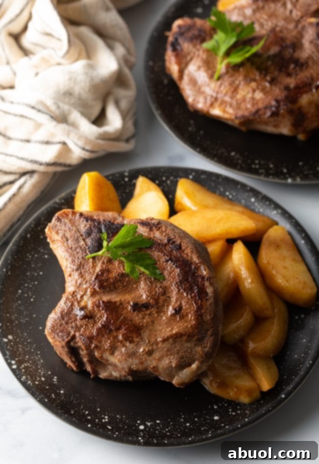 Thick Sous Vide Pork Chops on black plate with cinnamon apples