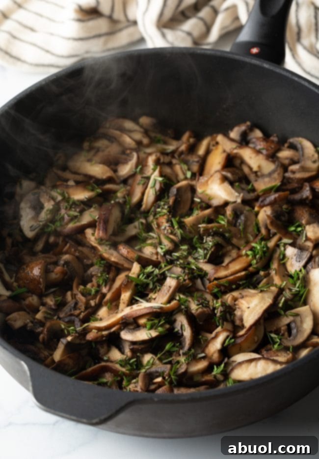 Sautéed mushrooms with fresh herbs and cooking sherry in a skillet.