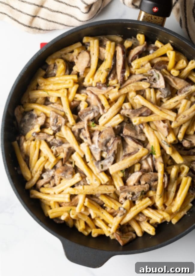 Top view of creamy Gemelli mushroom pasta in a heavy skillet, freshly prepared.