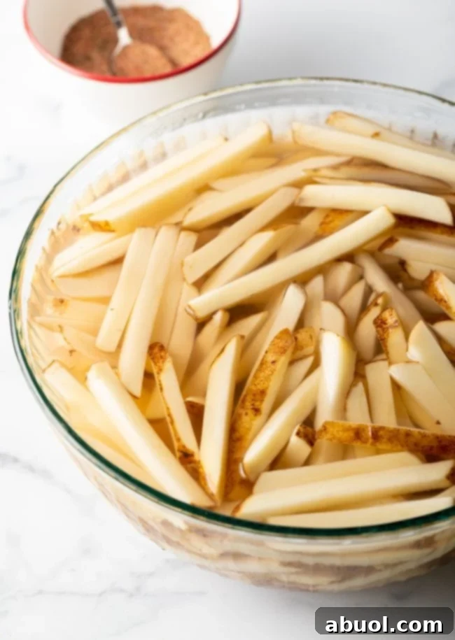 Potato slices in soaking in a bowl of water.