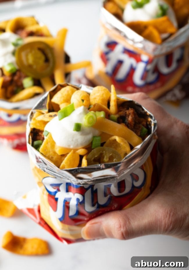 Hand holding bag of fritos with chili pie recipe made.