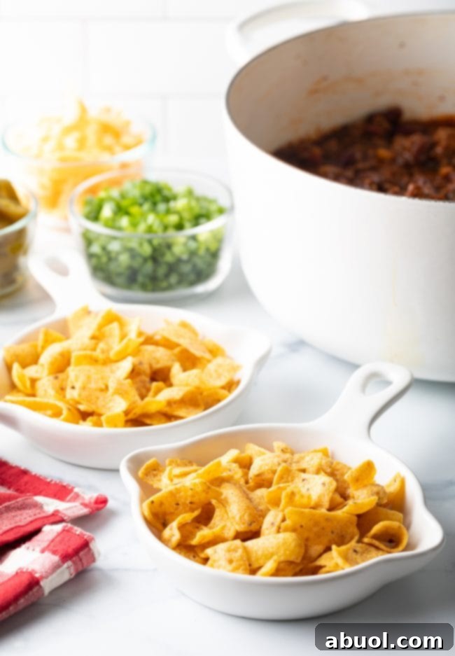 Corn chips in shallow dishes, with toppings in background.