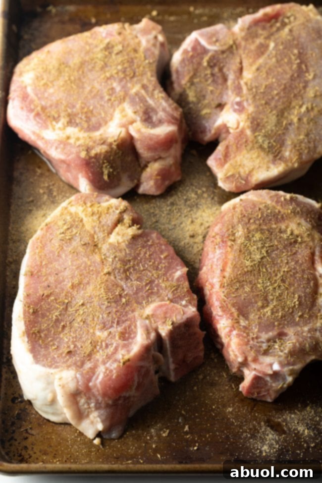 Seasoned pork chops laid out on a baking tray, ready for the smoker.