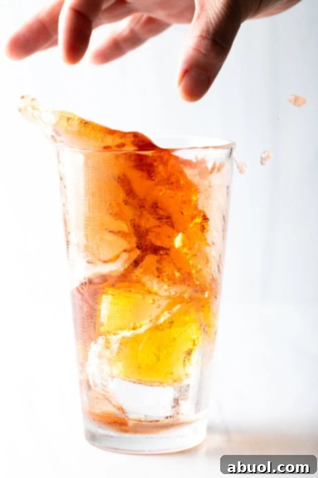 hand dropping energy drink shot into tall glass of juice and booze