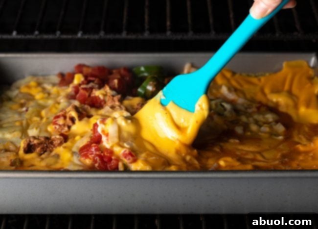 metal pan in a smoker, dip being stirred by spatula