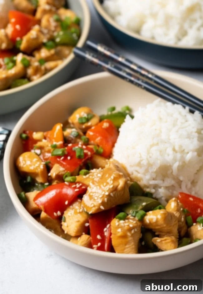 A top-down view of a bowl of Chinese garlic chicken with vibrant bell peppers, served alongside a scoop of pristine white rice.