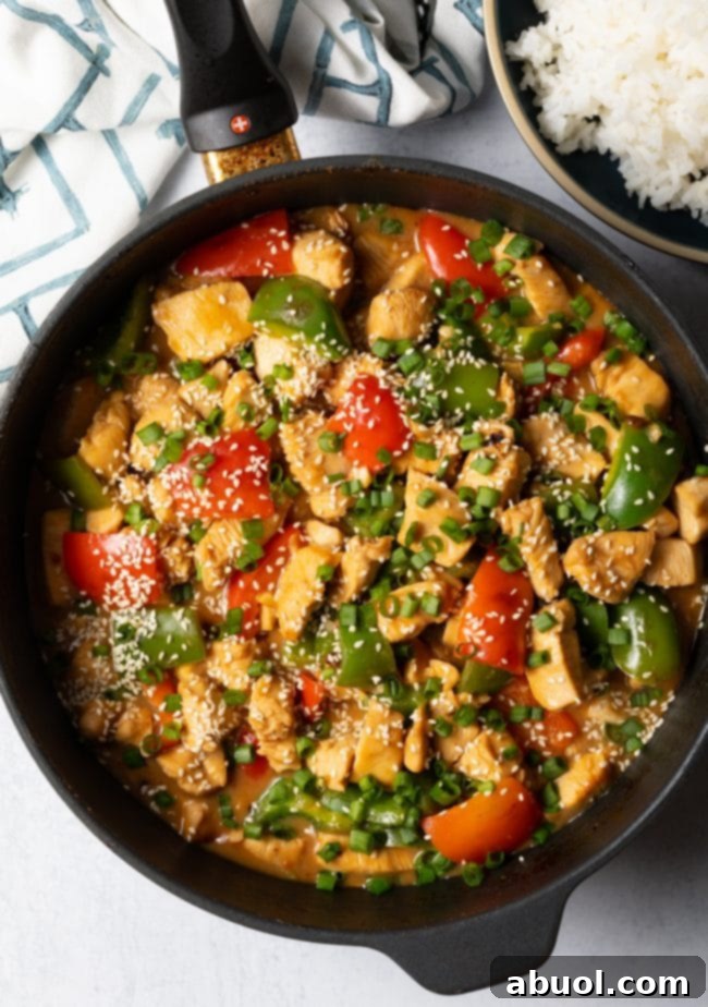 Another top-down perspective of the finished Chinese garlic chicken stir-fry in a skillet, beautifully topped with scallions and sesame seeds, showcasing its vibrant appeal.
