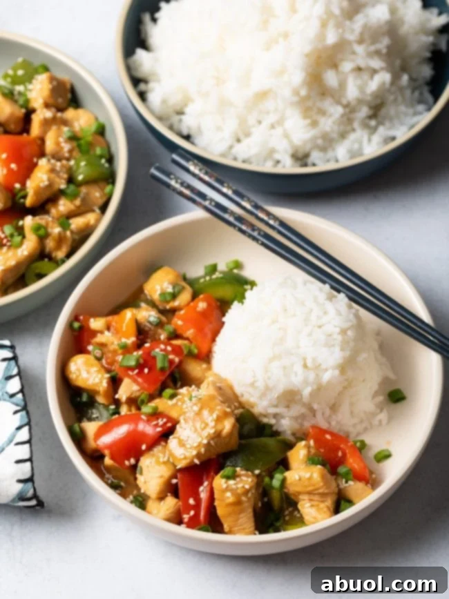 Another top view of two inviting bowls of chicken with garlic sauce and vegetables, each accompanied by a serving of white rice, emphasizing the deliciousness.