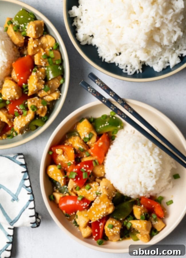Two bowls of Chinese garlic chicken and mixed bell peppers, each served with a generous scoop of white rice.