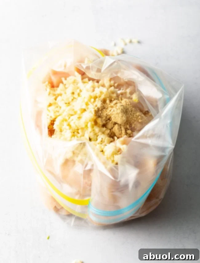 A sealed plastic Ziploc bag containing diced chicken pieces submerged in a savory garlic and soy sauce marinade.