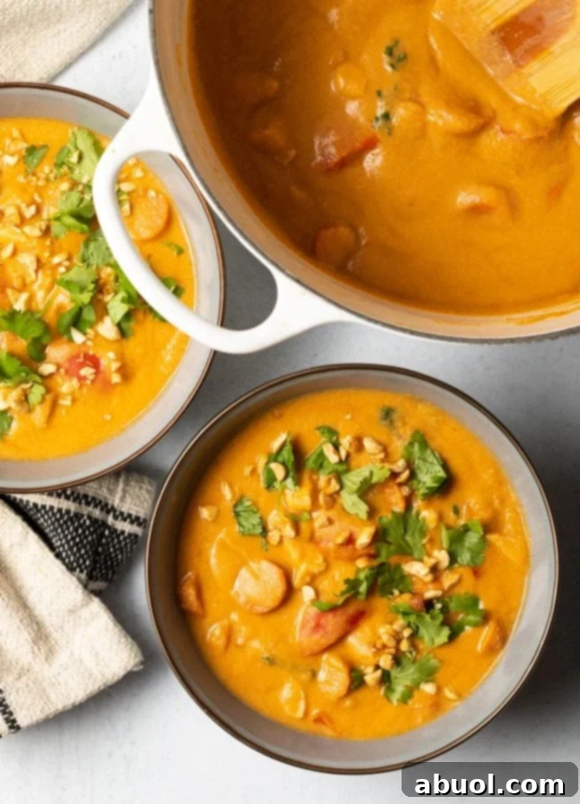Top-down view of two beautifully finished bowls of African peanut butter soup, generously garnished with fresh cilantro and crushed peanuts, ready to be served.