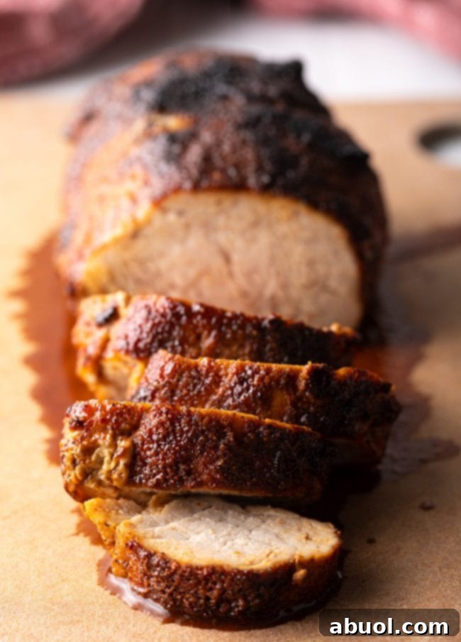 Air fried pork tenderloin in slices on a cutting board, garnished with fresh herbs.